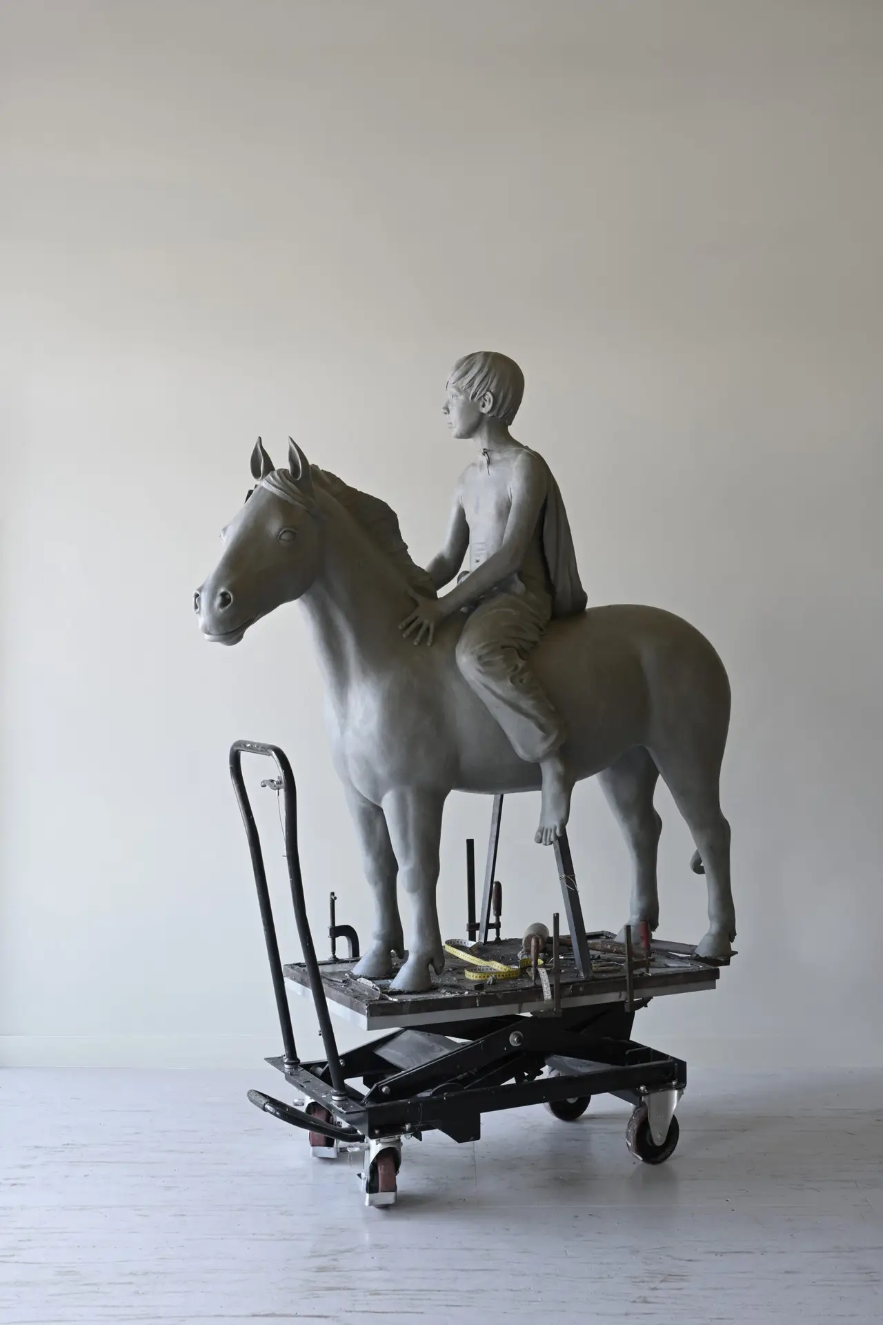 Klei sculptuur van jongen op pony op heftafel