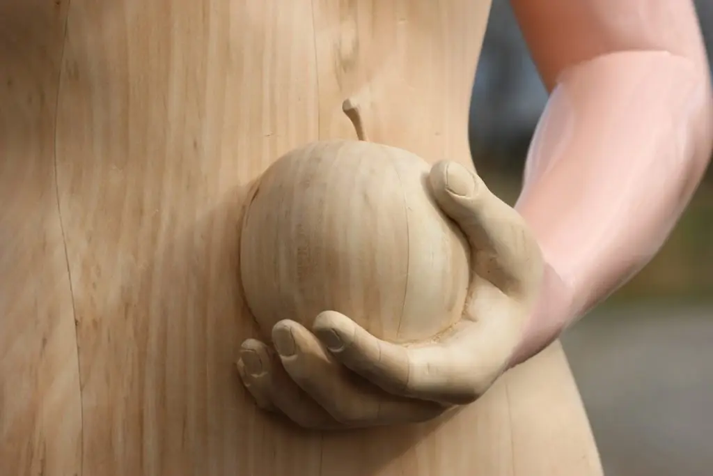 Detail van houten sculptuur van vrouw met appel
